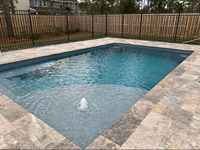 Fiberglass pool in a backyard with clear turquoise water and stone deck