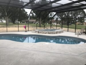 Fiberglass inground pool and spa in a sunny backyard with covered patio