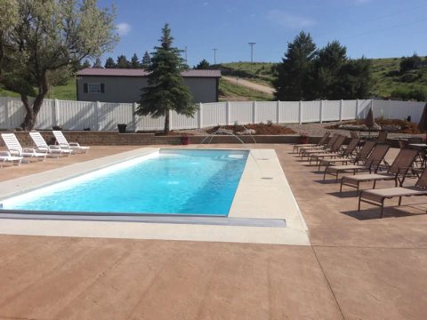 Rectangular fiberglass pool with clear turquoise water in a sunny backyard