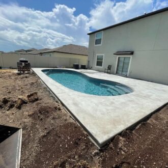 Fiberglass pool under construction in a backyard with clear turquoise water