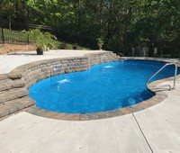 Fiberglass inground pool with turquoise water in a backyard setting
