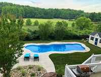 Finished freeform fiberglass pool with turquoise water in a backyard setting